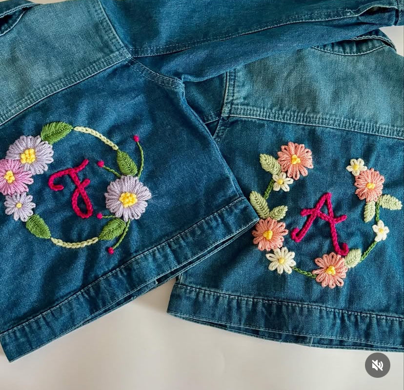 Denim jacket with floral embroidery and initials on a white background
