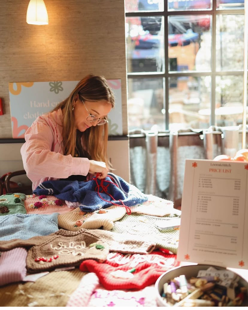 Woman working on a craft project in a cozy indoor setting with a window in the background.